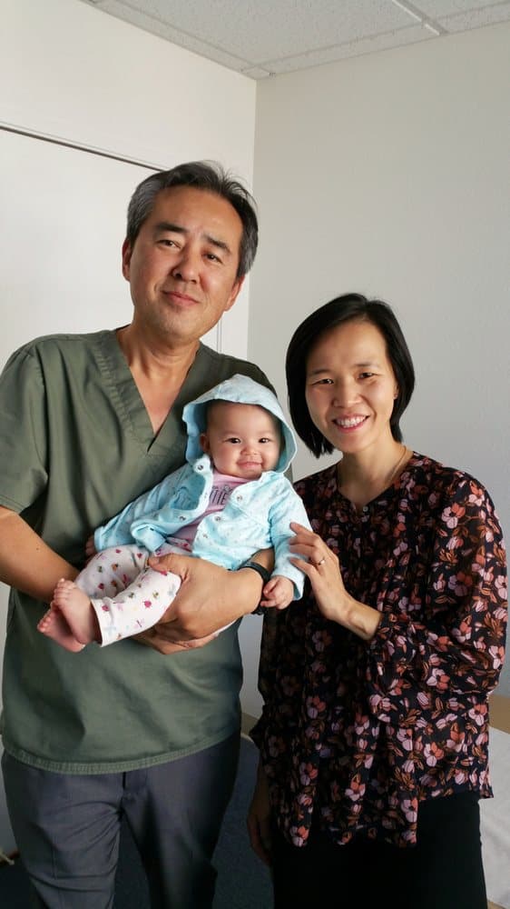 Dr. Ryu holding a smiling infant patient at the clinic